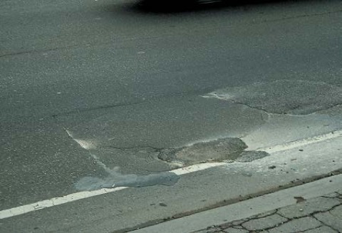 An old asphalt patch breaking up at its edges.